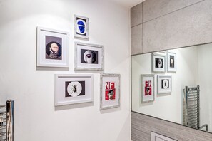 A wall with framed pictures and a mirror reflecting additional frames. - Modern Surrey Quays Flat (London)