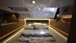 A narrow, well-lit bedroom with a bed centered in the room, wooden paneling on the walls, and a ceiling light. - Sun-Kissed Sailing Adventure in Zadar, Croatia (Zadar)