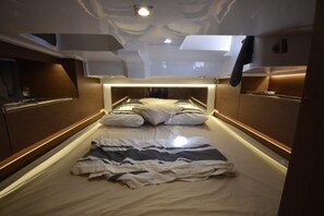 Ein schmales, gut beleuchtetes Schlafzimmer mit einem in der Mitte stehenden Bett, Holzvertäfelung an den Wänden und einer Deckenleuchte.
