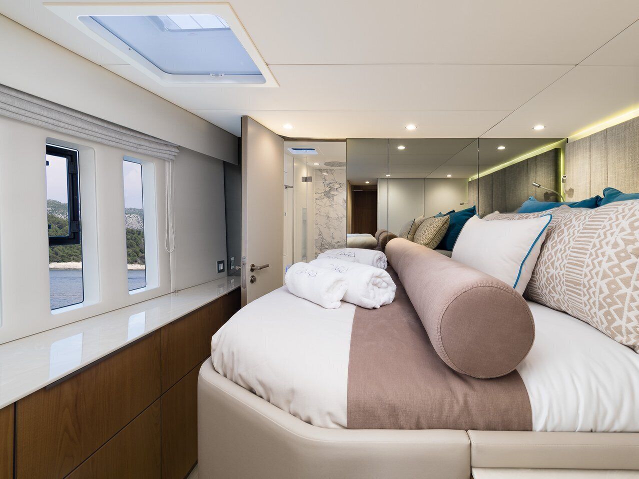 Un interno moderno con un letto, un lucernario e vista sull'esterno.