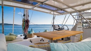 L'intérieur d'un bateau, avec une table en bois, des sièges rembourrés et une vue sur la mer.