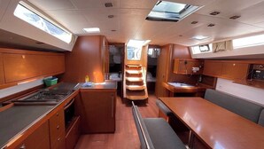 Cocina compacta con estufa, lavamanos y armarios de madera. Hay una zona de comedor con banco y mesa.