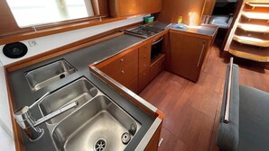 Una cocina pequeña y funcional con dos fregaderos, una estufa y armarios de madera.