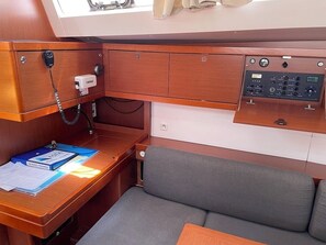 A compact cabin with a wooden desk, a control panel, a cushioned seat, and a window. - Sun-Kissed Sailing Adventure in Zadar, Croatia (Bibinje)