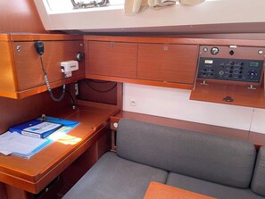 A compact cabin with a wooden desk, a control panel, a cushioned seat, and a window. - Sun-Kissed Sailing Adventure in Zadar, Croatia (Bibinje)