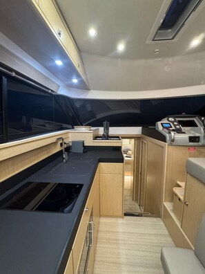 A compact galley with a stove, sink, and a control panel, likely for a boat or yacht. - Sun-kissed Sailing Adventure in Split-Dalmatia, Croatia (Trogir)