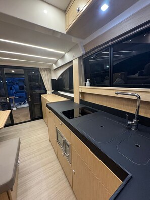 Une cuisine moderne avec un plan de travail noir, un évier en acier inoxydable et des armoires en bois.