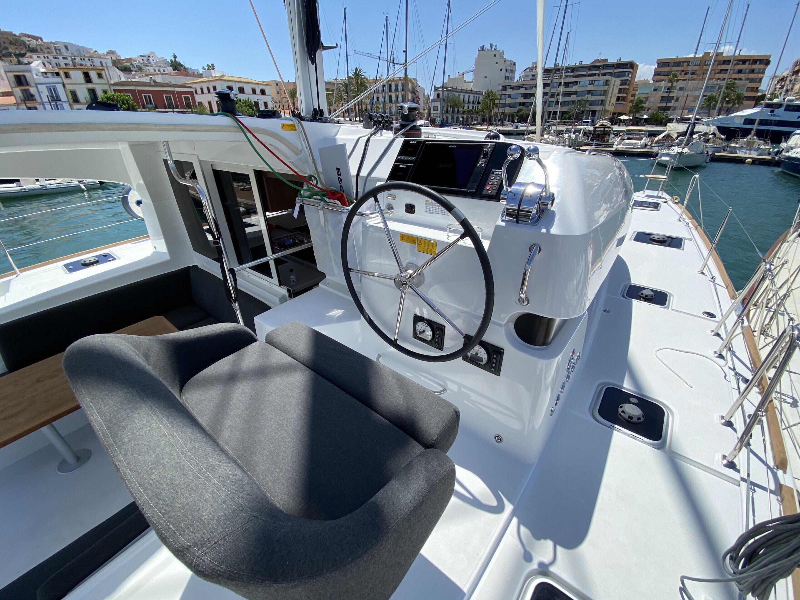 Cubierta de barco con timón, panel de control y zona de estar.