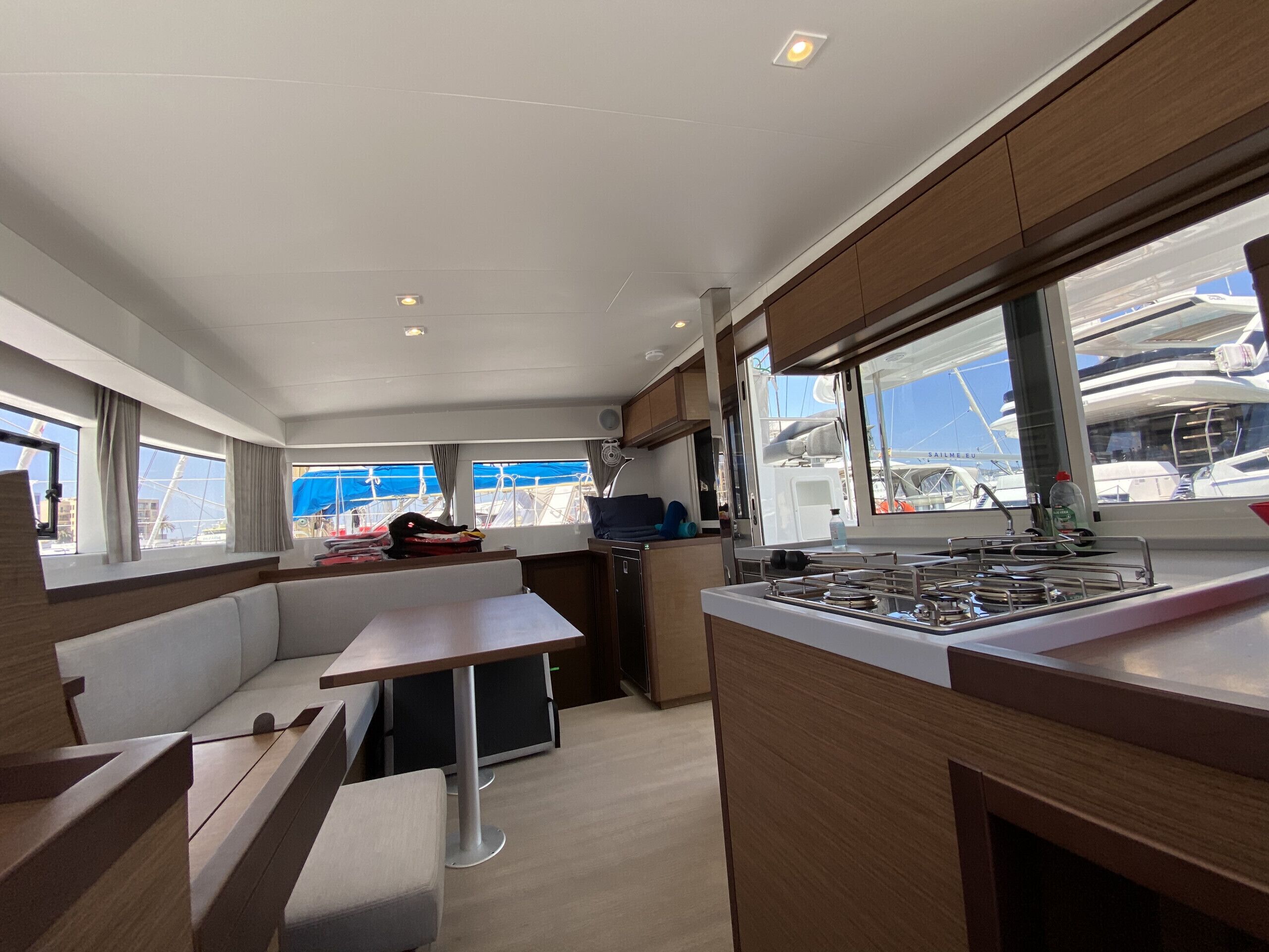 A modern kitchen with a dining area, large windows, and a view of boats outside.