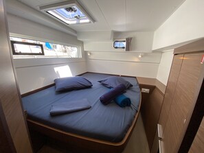 Una habitación pequeña con una cama, un ventanal y un tragaluz.