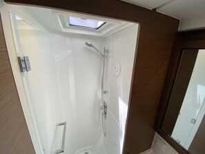 Un baño con tragaluz, ducha y espejo.