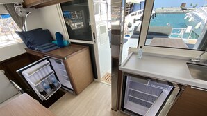Een kleine keuken met een koelkast, een spoelbak en een raam met uitzicht op een jachthaven.