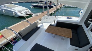 Een jachtdek met een zithoek, een tafel, en uitzicht op andere boten in de jachthaven.
