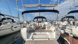 A marina with multiple sailboats docked, featuring a wooden deck, steering wheel, and a covered area.