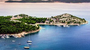 A coastal area with boats docked, a small island with buildings, and a clear view of the sea.