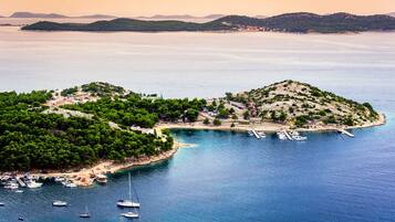 A coastal area with boats docked, a small island with buildings, and a clear view of the sea.