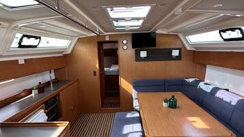 A compact galley with a wooden countertop, a bench, and a table with cushions.