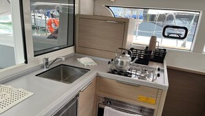 Una cucina compatta con lavello, fornelli e finestra vista acqua.
