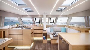 A modern yacht interior with a kitchen, dining area, and seating.