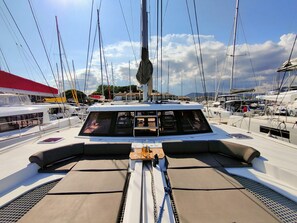 Ein Yachthafen mit mehreren Segelbooten, einem überdachten Bereich mit Sitzgelegenheiten und blauem Himmel.