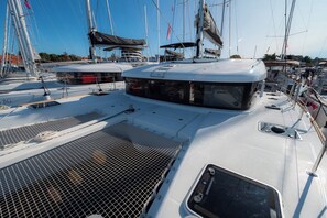 Ein Yachthafen mit mehreren Segelbooten, darunter ein überdachter Deckbereich und ein Netzabschnitt.