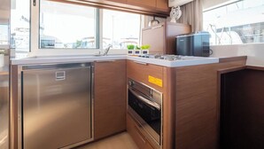 A compact kitchen with a built-in refrigerator, oven, and a window providing a view of the outside. - Sun-Kissed Sailing Adventure in Zadar, Croatia (Biograd na moru)