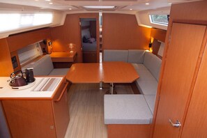 A compact interior with a central table, cushioned seating, a small kitchenette, and a window. - Sibenik Sun-soaked Sailing: A Luxurious Croatian Voyage (Pirovac)