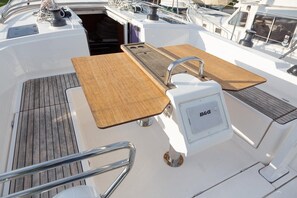 Das Deck eines Bootes mit einem Holztisch, einem Spülbecken der Marke B&G und einem Metallgeländer.