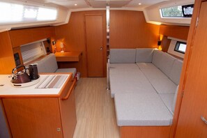A compact interior with a kitchenette, a cushioned seating area, and a door leading to another room. - Sibenik Sun-soaked Sailing: A Luxurious Croatian Voyage (Pirovac)