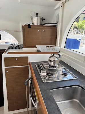 A compact kitchen with a stove, sink, and wooden cabinets.
