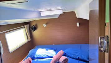 Habitación pequeña con cama, dos almohadas y ventana.