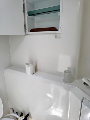 A bathroom with a white sink, a mirror, and a cabinet above the sink.