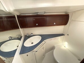 Een kleine badkamer met twee wasbakken, toilet en een kast met lades.