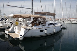 A marina with multiple sailboats docked, featuring a covered deck area and a cabin with windows. - Sibenik Sun-soaked Sailing: A Luxurious Croatian Voyage (Pirovac)