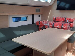 A compact interior with a sofa, a small table, a TV, and life jackets stacked in the corner. - Sun-kissed Sailing Adventure in Split-Dalmatia, Croatia (Trogir)