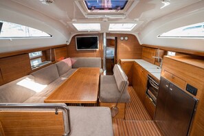 A compact galley with a dining table, seating, a television, and a compact kitchenette. - Sibenik Sun-soaked Sailing: A Luxurious Croatian Voyage (Pirovac)