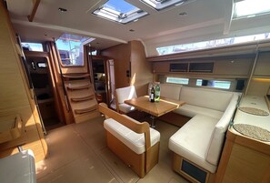 A compact interior with a dining area, seating, and a small table with bottles. - Sibenik Sun-soaked Sailing: A Luxurious Croatian Voyage (Pirovac)
