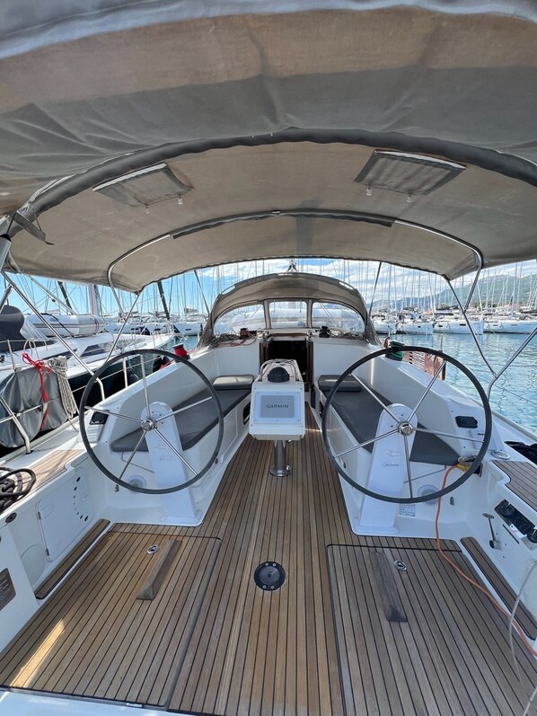 A boat's deck with a steering wheel, a Garmin device, and a canopy overhead. - Sun-Kissed Sailing Adventure in Split, Croatia (Kaštel Gomilica)