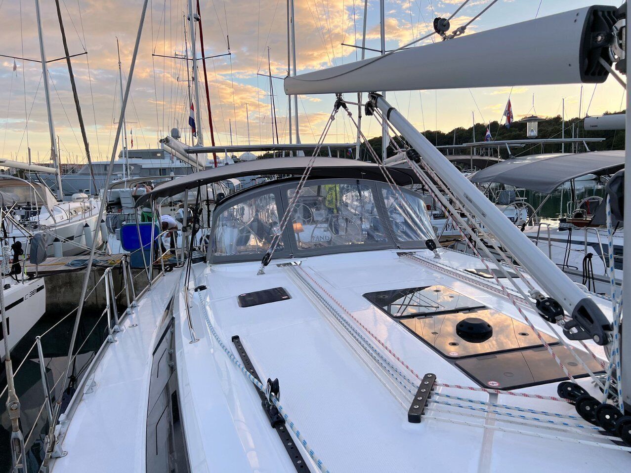 Un port esportiu amb diversos velers amarrats, que inclou una terrassa blanca amb una finestra central i un pal.