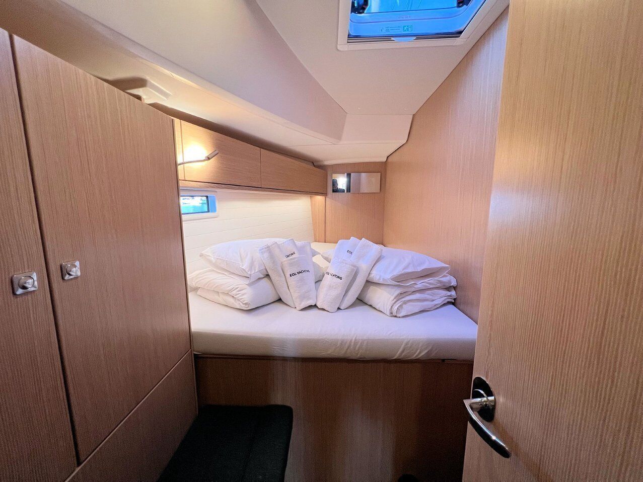 Una cabina compatta con un letto, cuscini e un piccolo oblò.