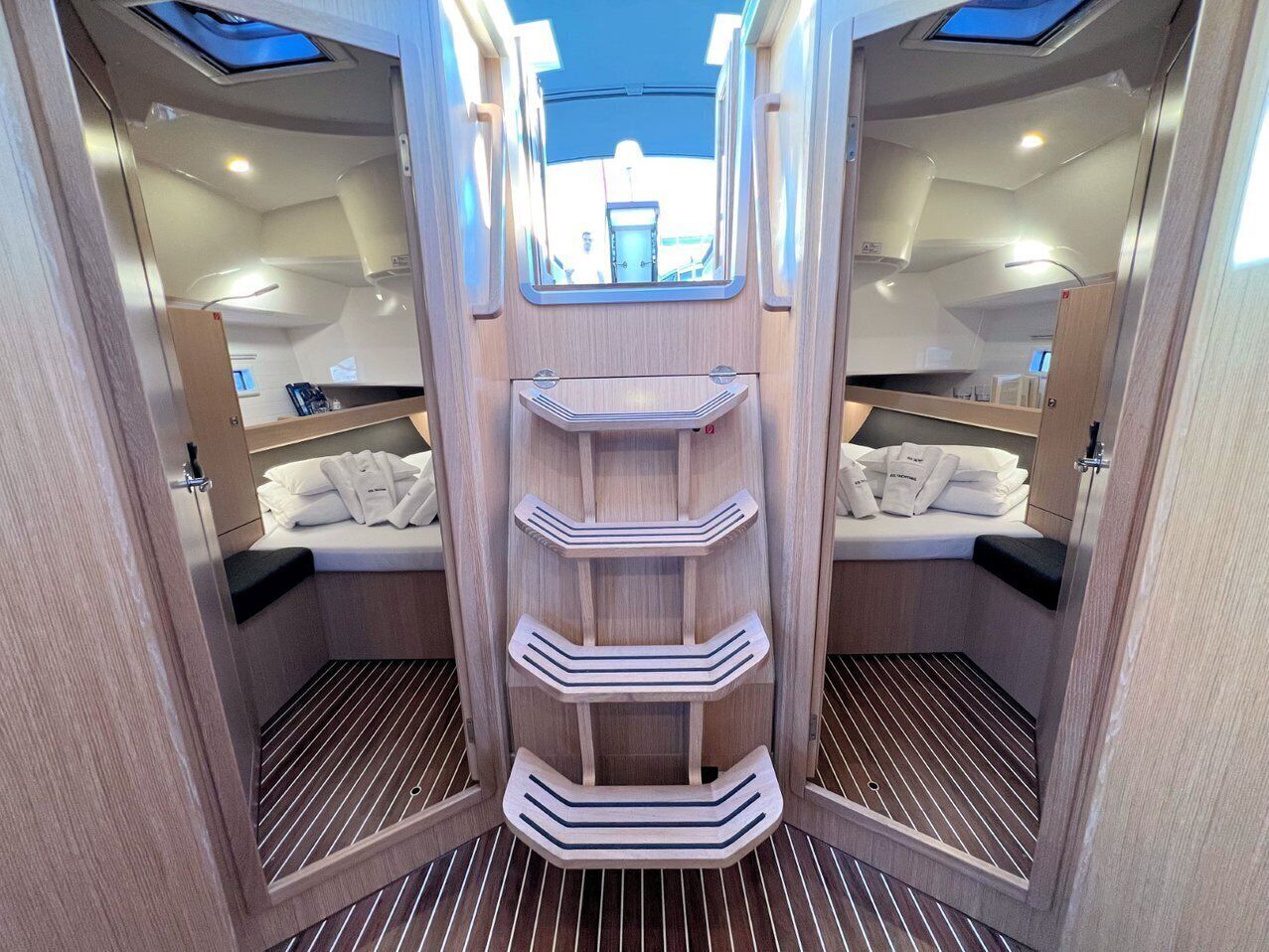 A compact, well-lit interior with a central shelving unit, mirrored walls, and a window at the top.
