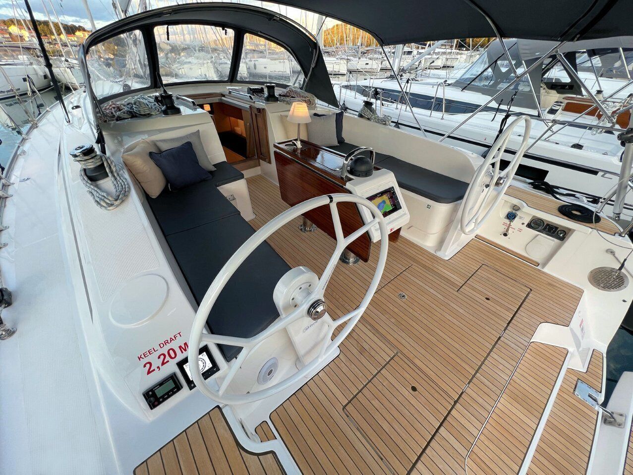 Cubierta de barco con timón, panel de control y zona de estar.