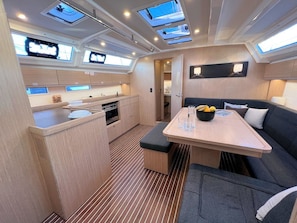 A compact kitchen with a dining area, a bench, and a table with a bowl of fruit. - Sun-Kissed Sailing Adventure in Istria, Croatia (Pula)