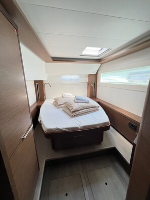 Ein kompakter, gut beleuchteter Raum mit einem Bett, einem kleinen Fenster und einem Oberlicht.