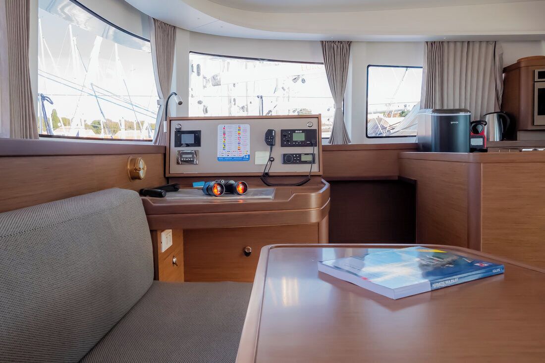 A compact, well-lit cabin with a control panel, a small table with a book, and a sofa.
