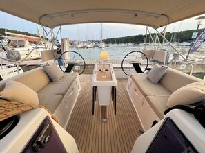 Ein Bootsdeck mit zwei Sofas, einem kleinen Tisch und Blick auf einen Hafen.