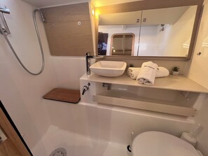 A compact bathroom with a bathtub, a sink, a mirror, and a towel rack. - Sun-Kissed Sailing Adventure in Istria, Croatia (Pula)
