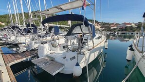 A marina with multiple sailboats docked, a covered deck area, and a clear view of the surrounding buildings. - Sun-Kissed Sailing Adventure in Zadar, Croatia (Drage)