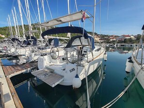 A marina with multiple sailboats docked, a covered deck area, and a clear view of the surrounding buildings. - Sun-Kissed Sailing Adventure in Zadar, Croatia (Drage)