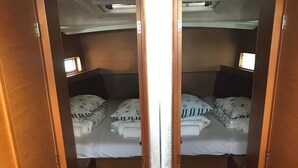 A compact cabin with two beds, each with pillows and blankets, and a small window providing natural light. - Sun-kissed Sailing Adventure in Split-Dalmatia, Croatia (Seget Donji)